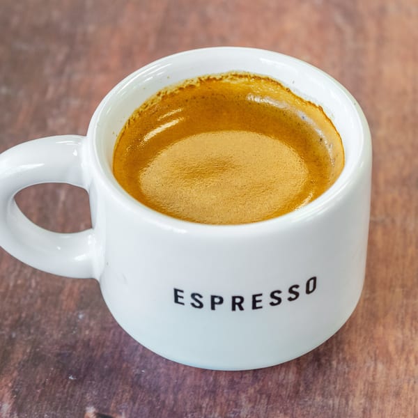 A white Chelsea Coffee Company espresso cup filled with rich, dark coffee and golden crema.